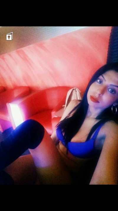 Mayah taking a picture as she sits on a chair in blue lingerie