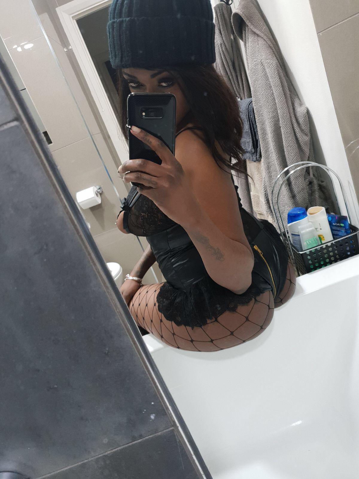 Nikki taking a picture in a mirror wearing very sexy leather underwear