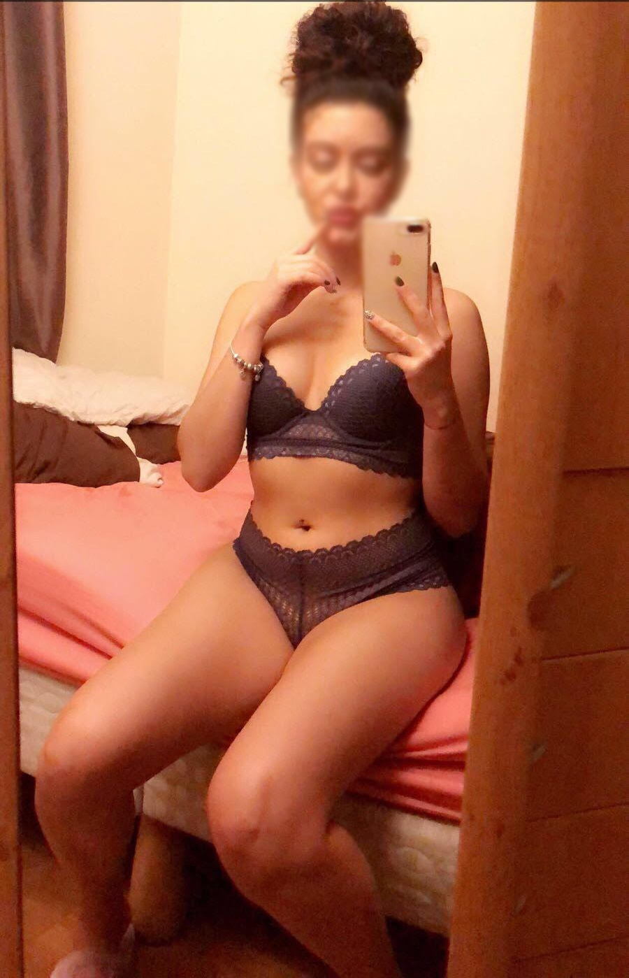 Lizzie taking a selfie in blue lingerie as she sits on her bed