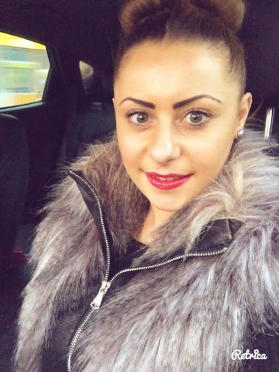Selfie of Sasha wearing fluffy leather jacket and bright red lipstick with her hair in a bun.